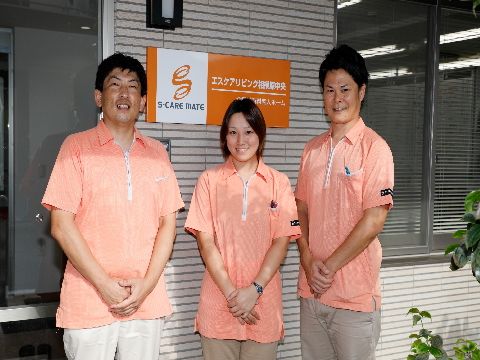 施設には男性と女性、幅広い年齢層のスタッフが在籍している。施設看板と同じオレンジ色の明るい制服が目立つ。