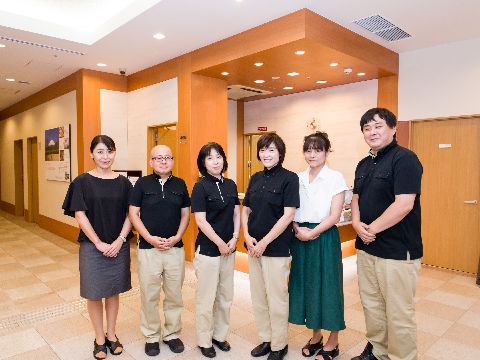 男女合わせて6名のスタッフが一列に並んでいる。黒いシャツにベージュのズボンや、白いシャツにスカートなど作業しやすい恰好をしている。