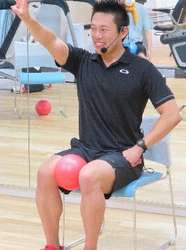 イスに座って運動を指導している男性