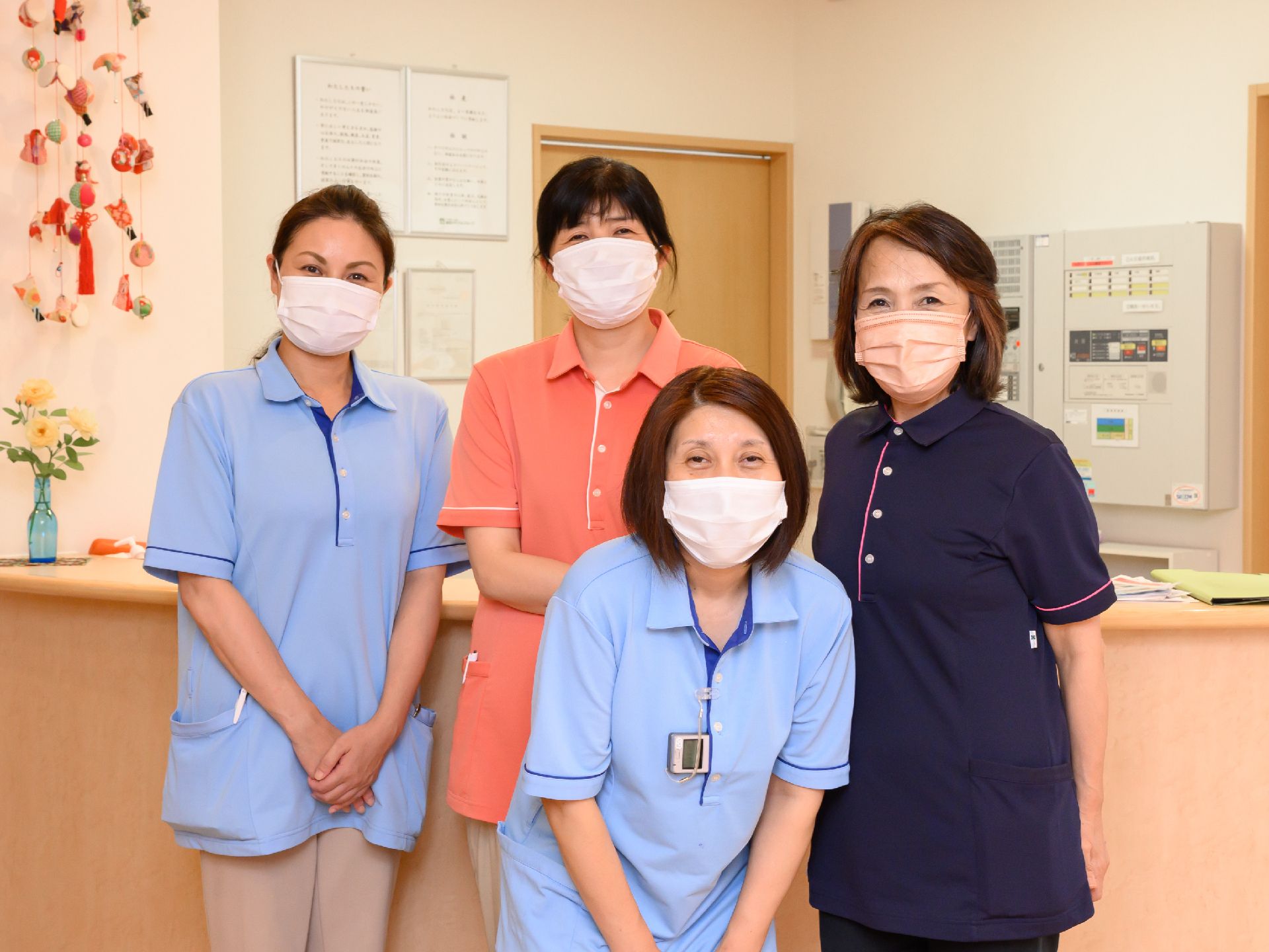 建物の受付の前に立っている４名の女性従業員