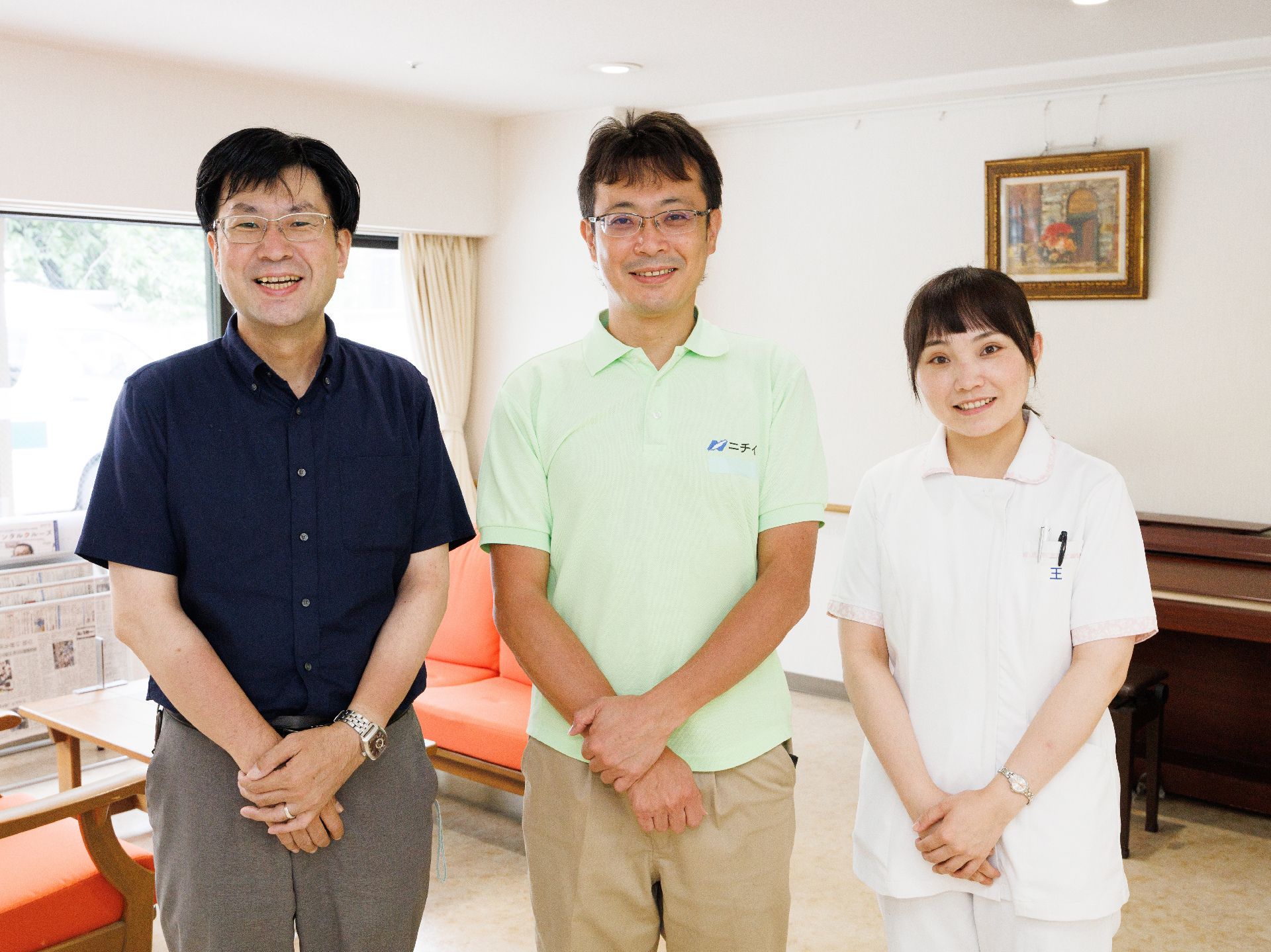 前で腕を組み並んで立っている３名の従業員