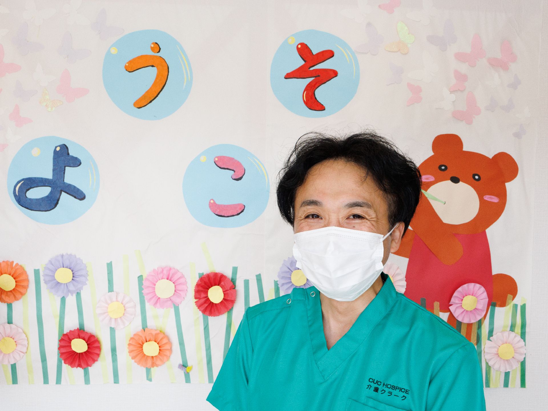 紙が貼られた白い壁の前に立っている男性従業員