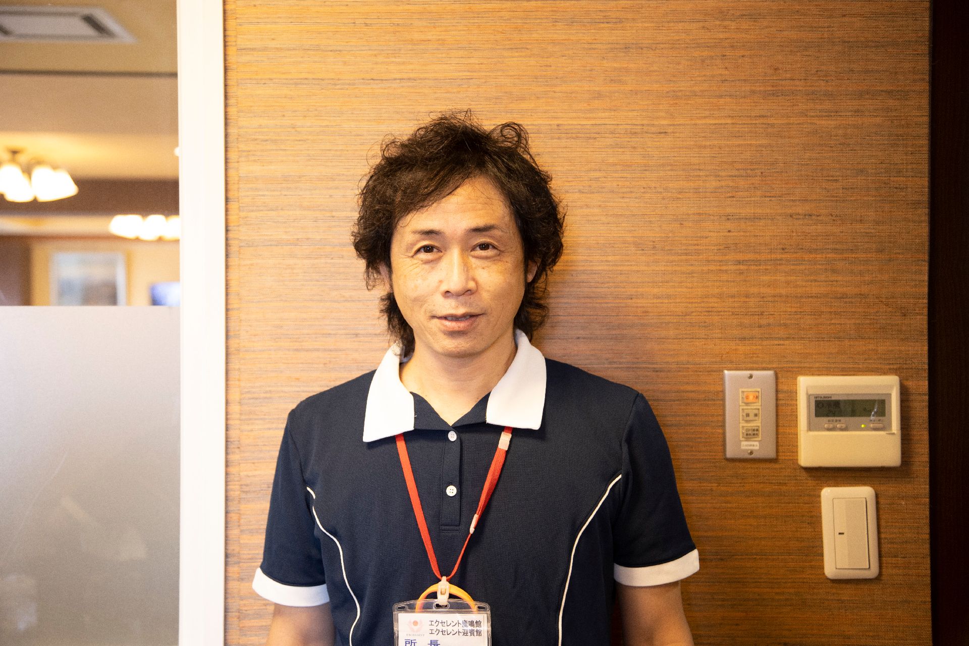 木製の壁の前に立っている男性従業員