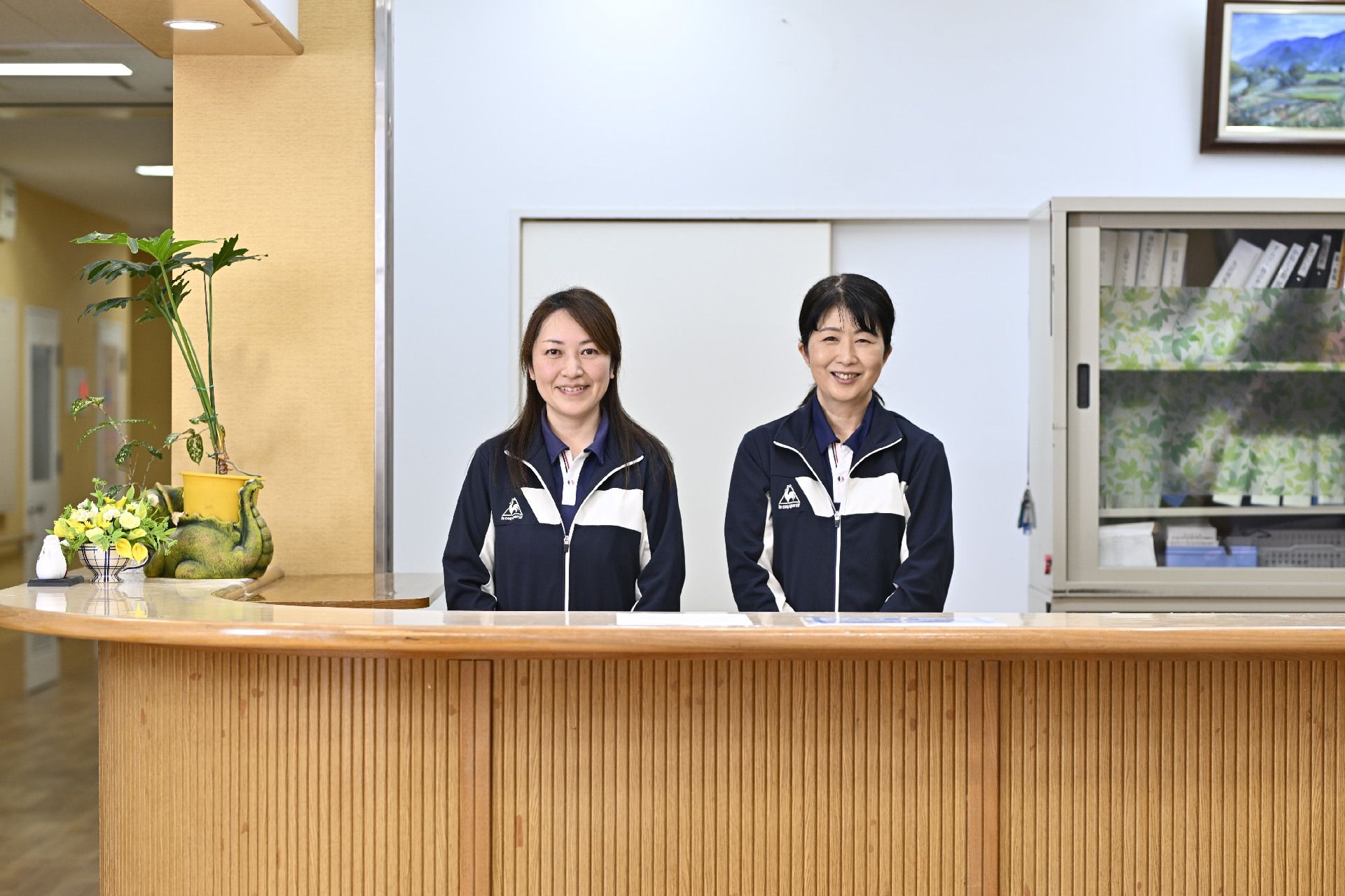 施設で働くスタッフの集合写真である。前列には3人の女性が椅子に座っており、後列には男性2人と女性3人が立っている。