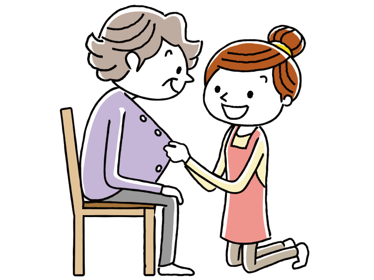介護福祉士にボタン止めをしてもらっている高齢女性