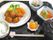 唐揚げをメインとしたボリューム満点の食事。野菜の小鉢が複数添えられ、白いご飯とみそ汁もある。