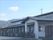 和風の建物は平屋建てで白と黒の落ち着いた色合い。周辺には緑が多く、明るい雰囲気。