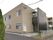 ブラウン系の２階建ての建物。白いフェンスや屋外階段もある。