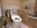 木製の壁に囲まれている施設内のトイレの様子。両側の手すりと緊急コールが写っている