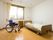 車いすや寝具付きのベッドが置かれた部屋にはカーテンが付いた大きな窓がある。