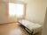 寝具付きのベッドが置かれたフローリングの部屋にはレースカーテンとカーテンが付いた大きな窓がある。