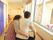 歩行器を使って廊下を歩く入居者残しに手をまわして話しかけている女性スタッフ。