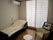 寝具付きのベッドが置かれたフローリングの部屋にはテーブルセットが置かれ、緊急通報装置もある。