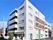 ５階建ての建物。白を基調とした清潔感のある外観で、すぐそばには広い駐車場もある。