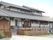 グレーの瓦屋根が付いた平屋建ての建物。平屋建ての建物は一部2階建てで庭もある。