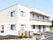 白を基調とした２階建ての建物は日当たり良好で建物の前には駐車場などがあり、2階部分にはベランダも付いている。