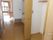クローゼットやキッチンが付いたフローリングの部屋には大きな窓があり、ピンクのカーテンが付いている。