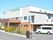 白とベージュの２階建ての建物は日当たりがいい場所に建っていて、敷地内には駐車場も完備されている。