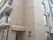 4階建てのブラウンを基調とした建物は一般のマンションのようなたたずまい。玄関横には住宅のロゴがある。