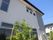 外壁に施設の名前が書かれた2階建ての建物。シンプルな色使いで周辺には緑が植えられている。