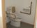 手すりや背もたれが付いた広いトイレにはスライド式のドアが設置されている。
