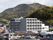 民家に囲まれたグレー系の大きな建物の外壁にはホーム名が書かれている。周りには山もある。