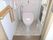 ピンク色のトイレはシンプルなデザイン。少し出入り口に段差があるが、手すりが設置されている。