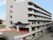 グレーの6階建ての建物はどっしりとしていて、1階部分が駐車場となっている。周りには背の高い建物はない。