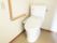 L字型の手すりがついている高齢者向けの施設のトイレ。シンプルな構造のトイレが写っている