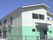 ２階建ての建物は上半分が白、下半分がグリーンの２色使い。玄関部分には屋根が付いている。