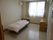 寝具付きのベッドやチェストが置かれた部屋にはレースカーテンとカーテンが付いた窓があり、エアコンもついている。