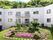 紫の花や木が植えられた中庭があり、その後ろには2階建ての建物が建っている。
