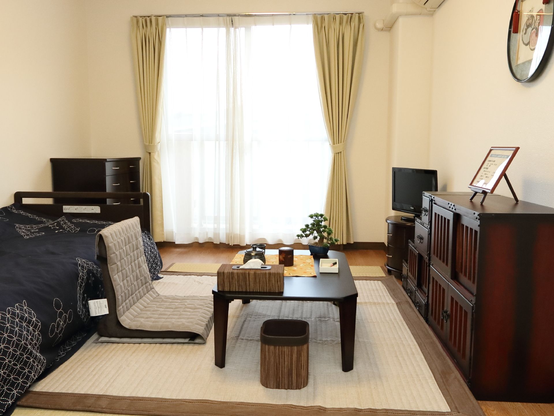 テーブル、テレビ、タンスがおいてあり住みやすい部屋。絵が飾ってあるなど遊び心も忘れていない。日当たり良好。