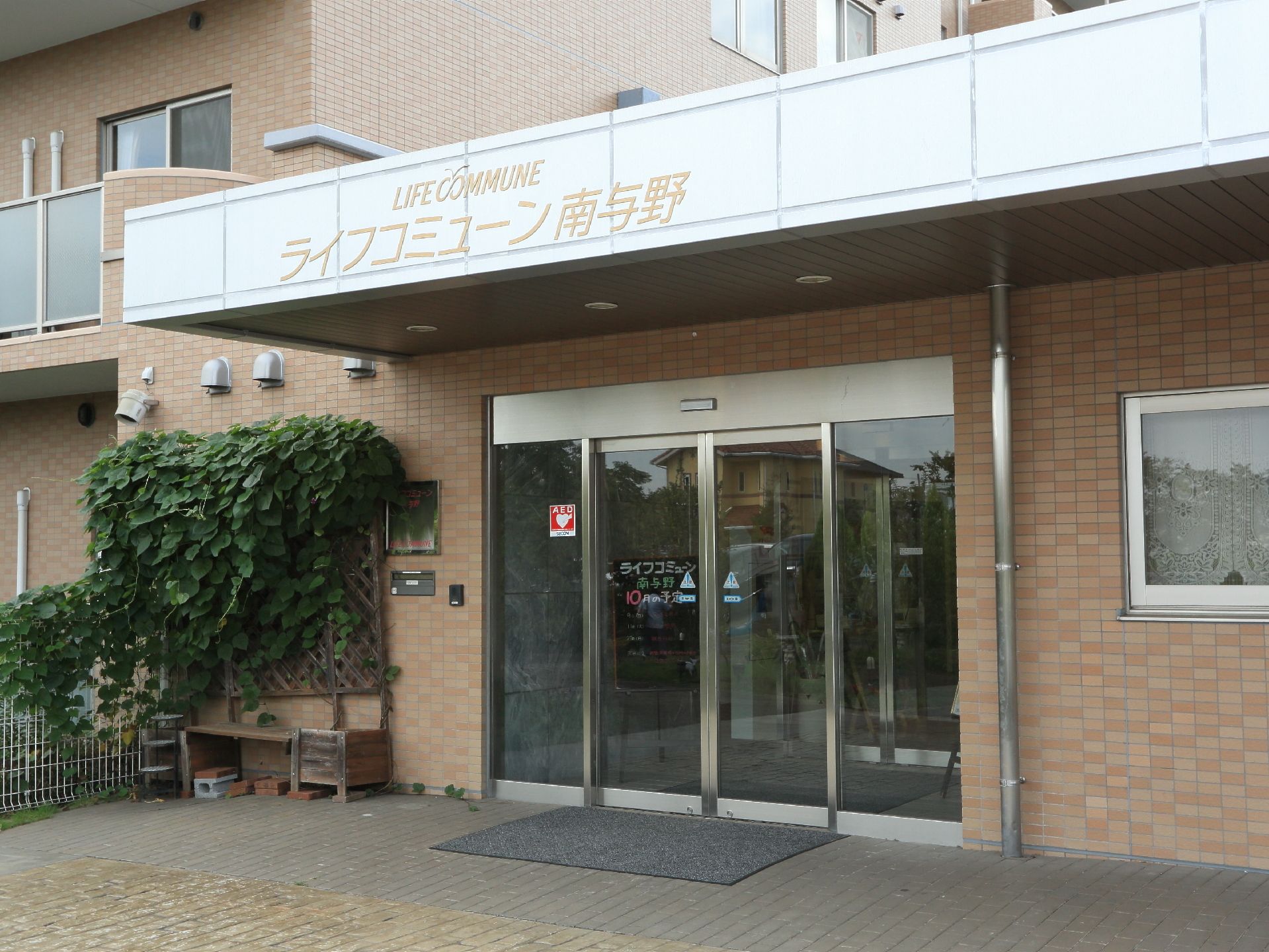 玄関は車いすでも通りやすいように広い作りになっている。左側には植物も植えられている。窓も設置されている。