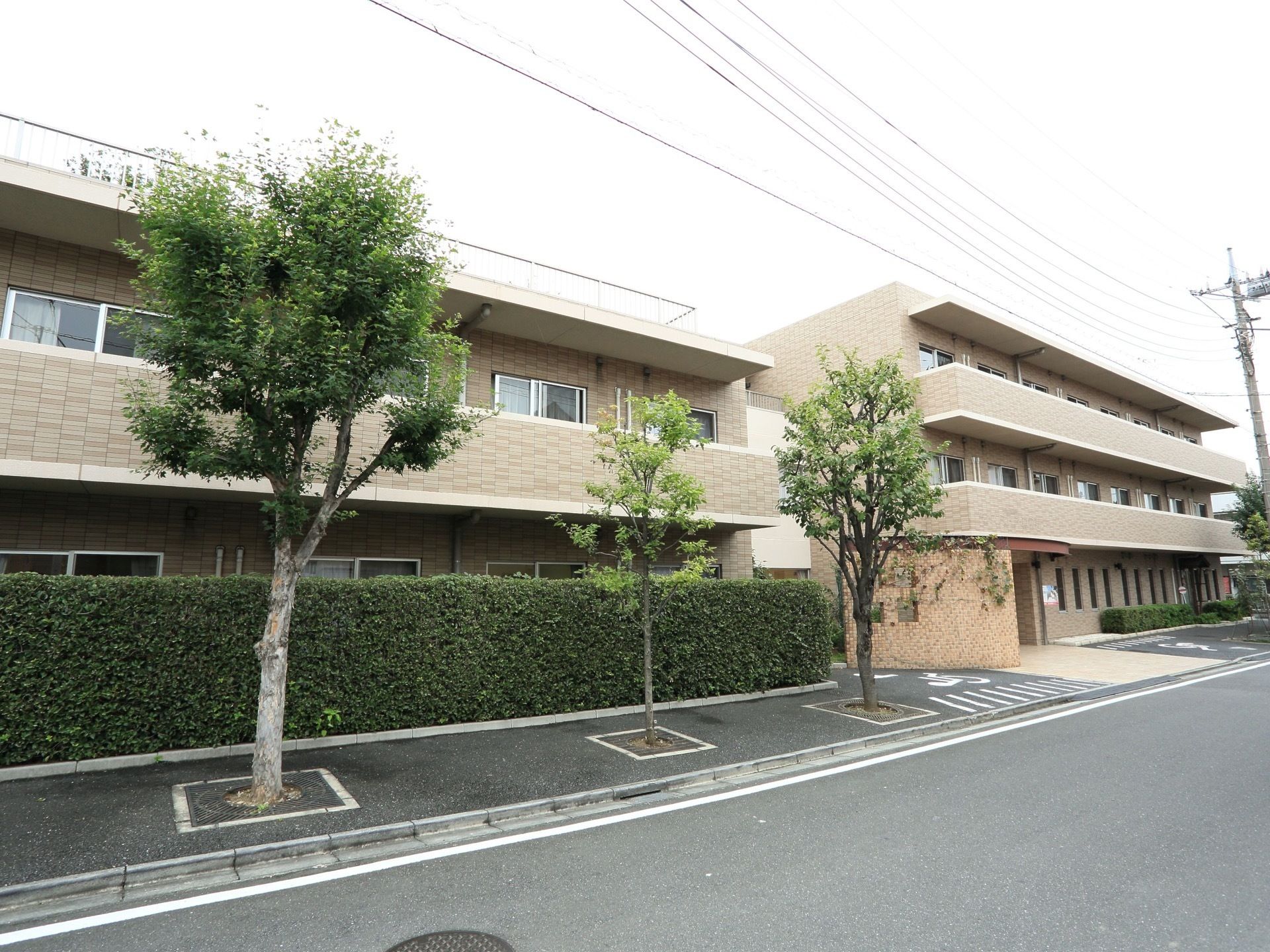 地上３階建ての施設を、斜め方向から写したものである。建物のすぐ横には植込みがあり、１階部分の窓が見えないように工夫してある。