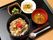 黒い角盆の上に丼、汁物、小鉢2つが乗っている。丼の他に野菜の煮物と、オクラの2つの小鉢がある。箸・スプーンが用意されている。