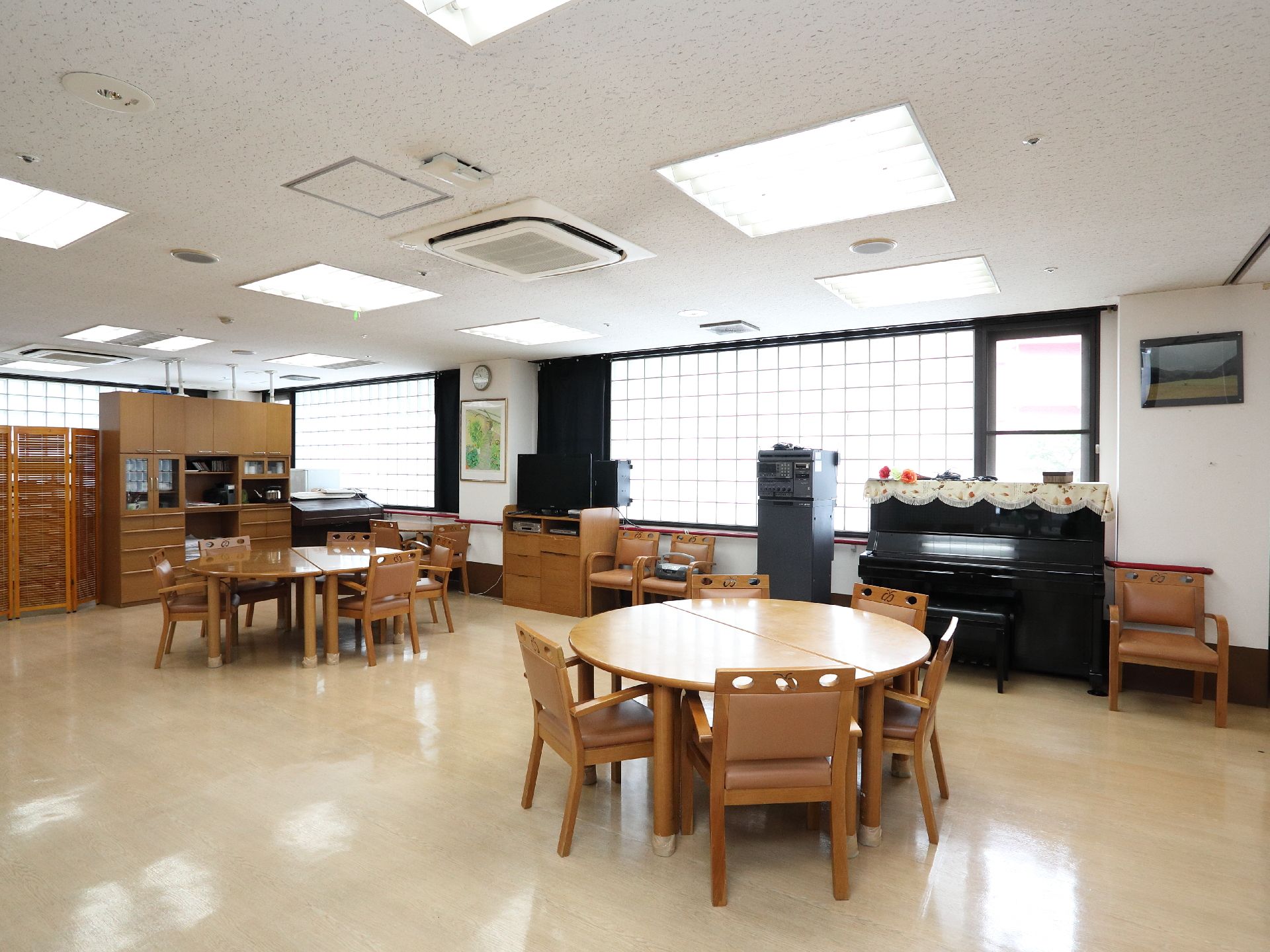 共用のリビングルームにはイスやテーブルが置かれている。またレクリエーションなどをおこなうため、ピアノも設置されている。