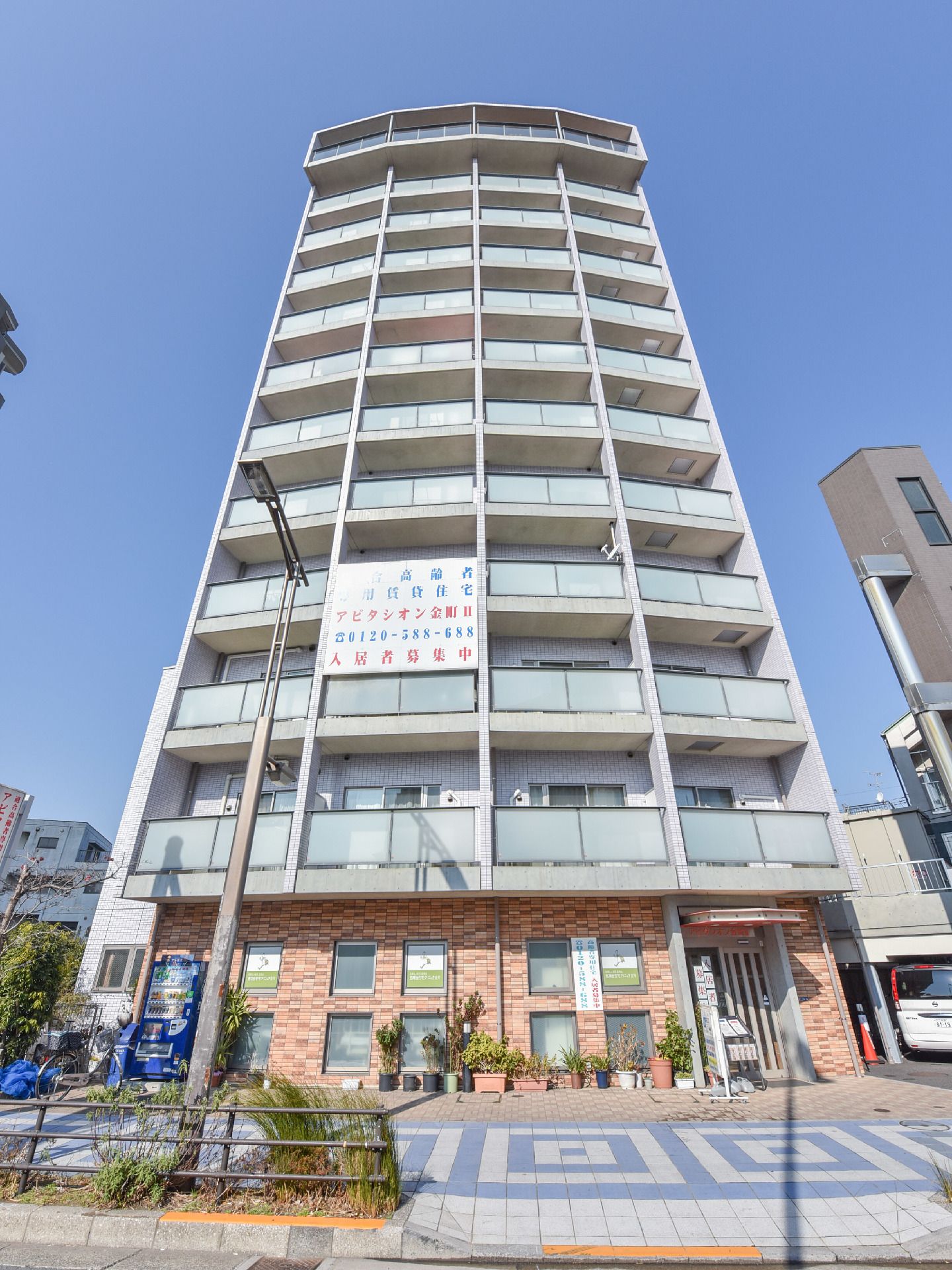 施設の外観は12階建てのマンションタイプになっている。二階以上が居室になっていて一階には出入り口とテナントがあるのが見える。
