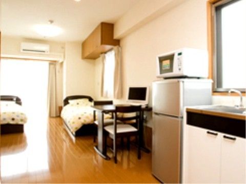 奥にベッドが二台設置されており、手前に冷蔵庫やキッチンのある居室