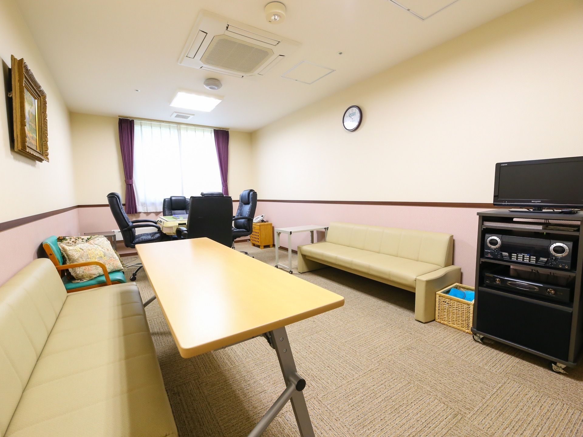 手前には長いソファとテレビ、コンポが設置されている。奥には麻雀卓があり、入居者様にとっての憩いの場である。