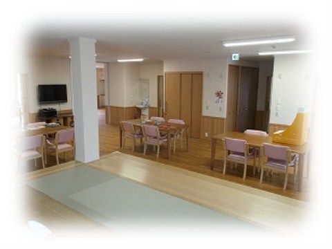 ４人掛けのテーブルとひじ掛け付きの椅子が複数セッティングされている。壁には、大きなテレビが設置されている。