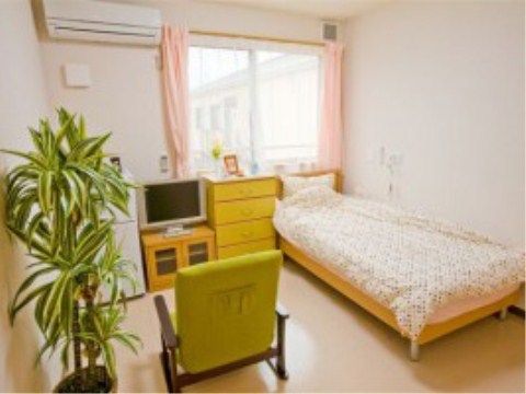 窓の手前に収納家具やテレビが置かれている、明るい印象の居室