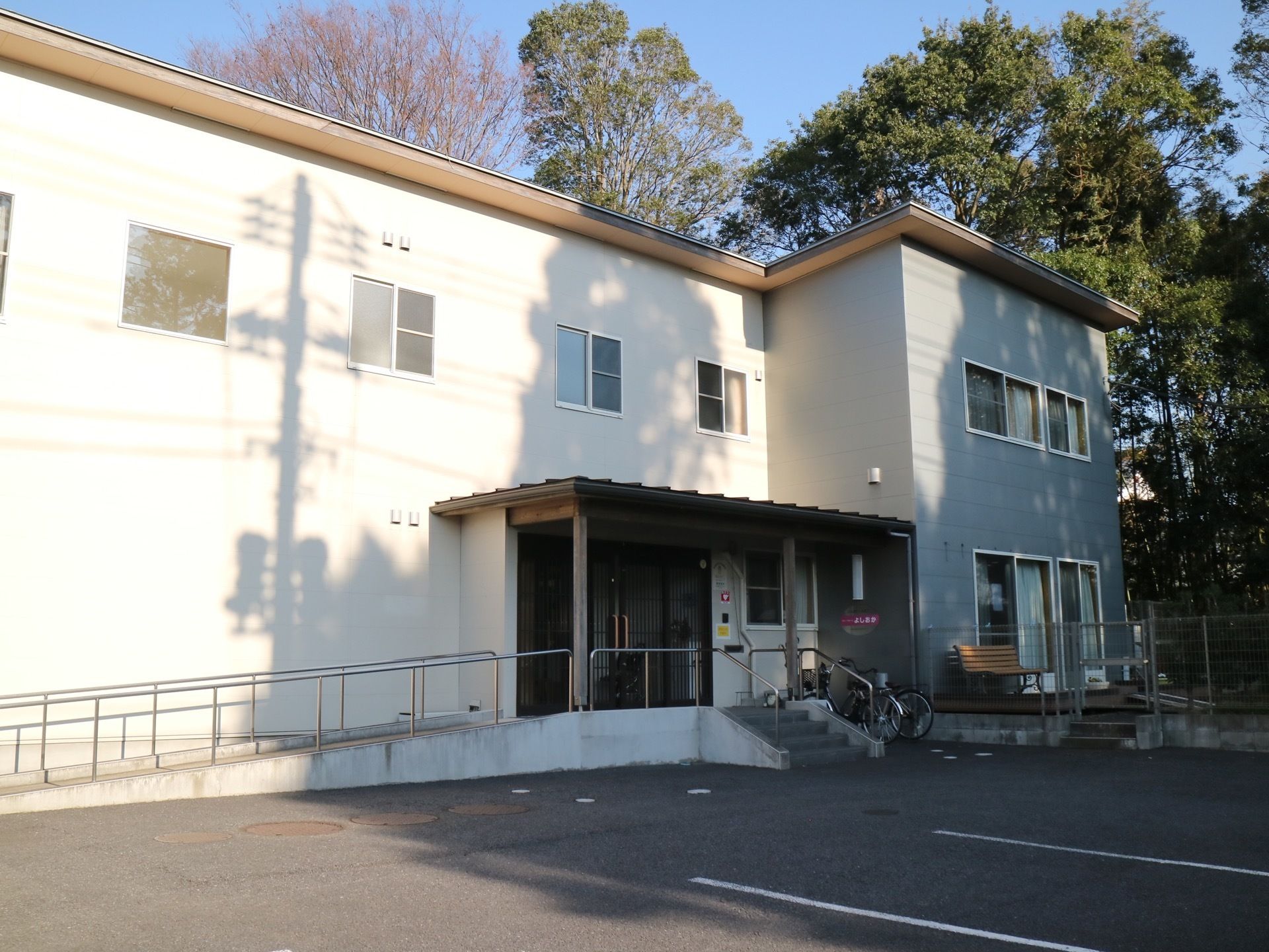 施設は、身近に自然を感じていただける環境である。玄関には屋根が設置されており、建物の前に複数台の自転車が停められている。
