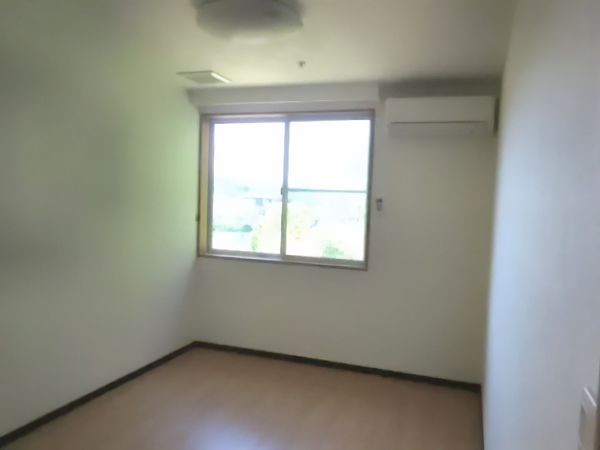 腰高の窓の右側の壁上部にエアコンが設置されている居室