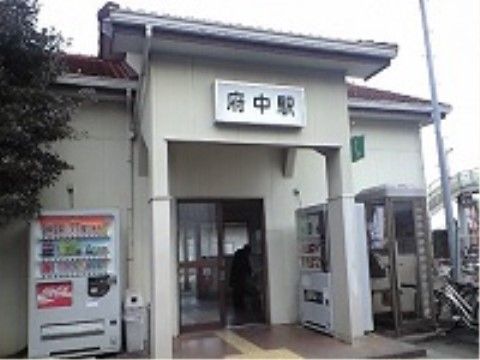 駅の入口。玄関ポーチには屋根があり、屋根の下と外に自動販売機が設置されている。地面には点字ブロックがある。