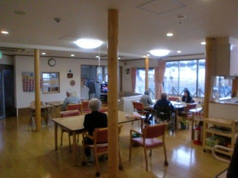年配の方々が何人か座っている、明るい色のフローリングの食堂
