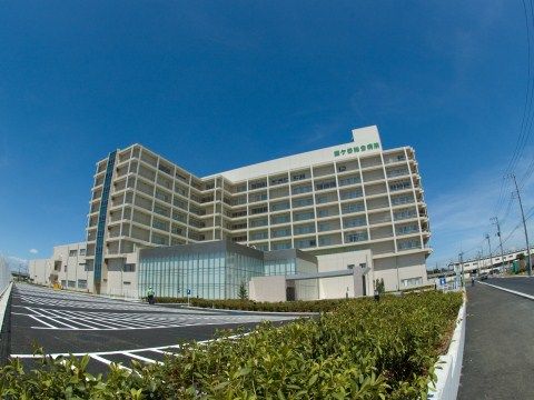 近隣の病院は近代的な外観の大きな建物で、駐車スペースも広く設けてある。緑色の文字で施設名が書かれている。