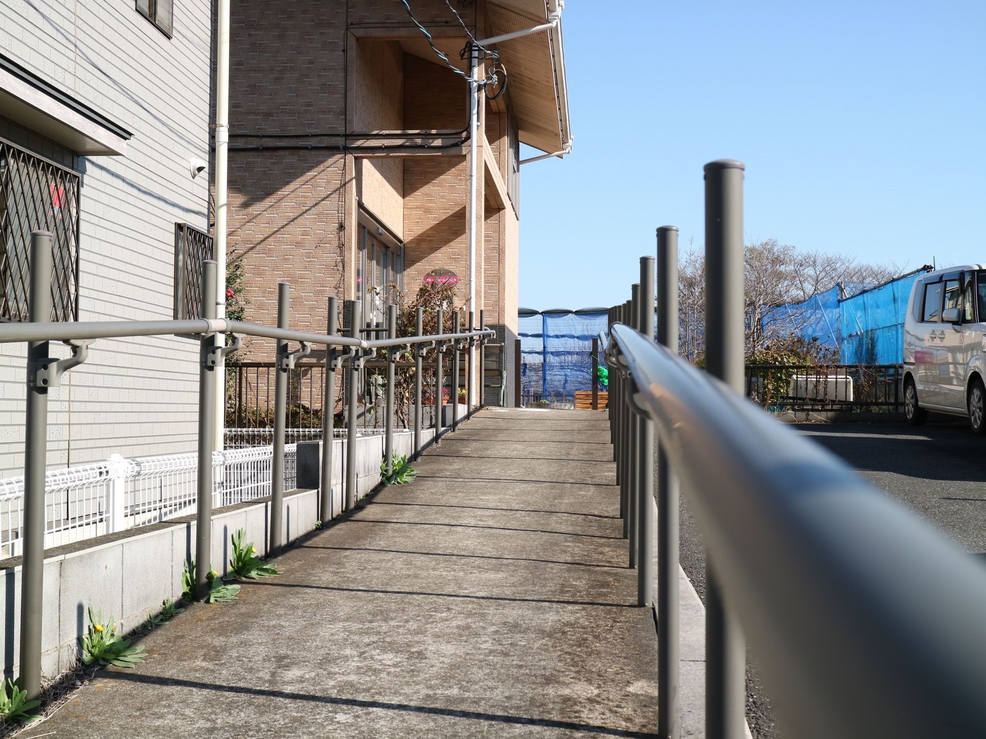 長方形の石が並べられた入口前の通路で、緩やかなスロープになっている。両側にはステンレス製の手すりが設置されている。