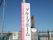 施設の入口に設置された施設名が書かれた看板の図である。白とピンクで塗り分けられた板に施設名が記載されている。
