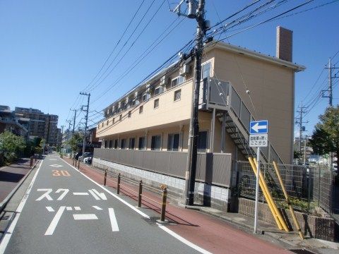 一方通行の道路に沿って立つ、2階建てで横長の茶色い建物